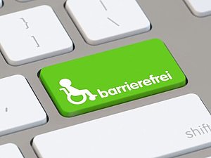 Weiße Tastatur mit einem grünen Taststein, daraut ein Rollstuhl mit einer Person und das Wort "barrierefrei"