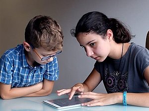 Maks sitzt mit seiner blinden Schwester Mia vor dem Tablet, Mia führt ihren Zeigenfinger über das Tablet , Copyright: Feelif