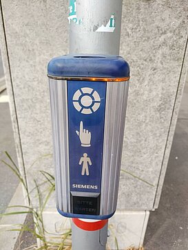 Akustikampel_Hilfsgemeinschaft_der_Blinden_und_Sehschwachen_OEsterreichs__3 blaue Akustik- und Gebrauchsampel mit grafiischem Hinweis, dass man drücken muss um zu gehen