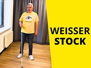 Mann steht mit Weißem Stock.