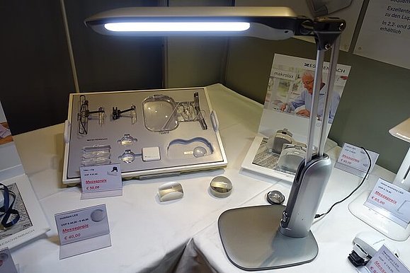 Neue LED-Tischleuchte sorgt für optimale Ausleuchtung Silberne LED-Tischleuchte mit Knopf am unteren Ende steht auf einem Tisch und leuchtet.