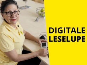 Frau hält ihre digitale Leselupe und blickt in die Kamera. Text: "Digitale Leselupe"