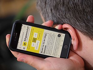 Mann hält sich Smartphone zum Hören ans Ohr